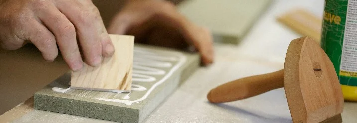 Person trägt Leim mit Spachtel auf
